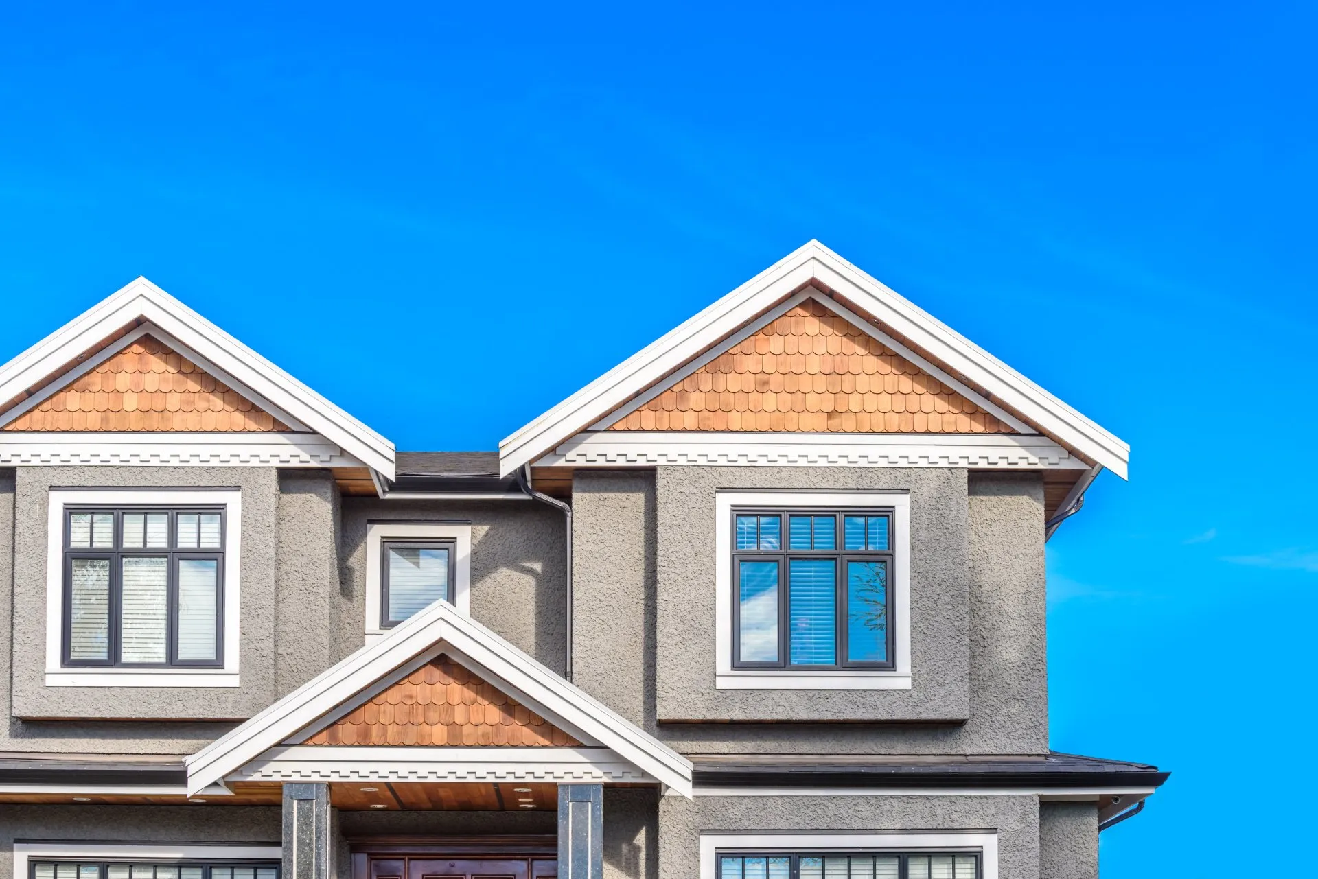 Gray stucco home exterior with white trim and wood shingle gables