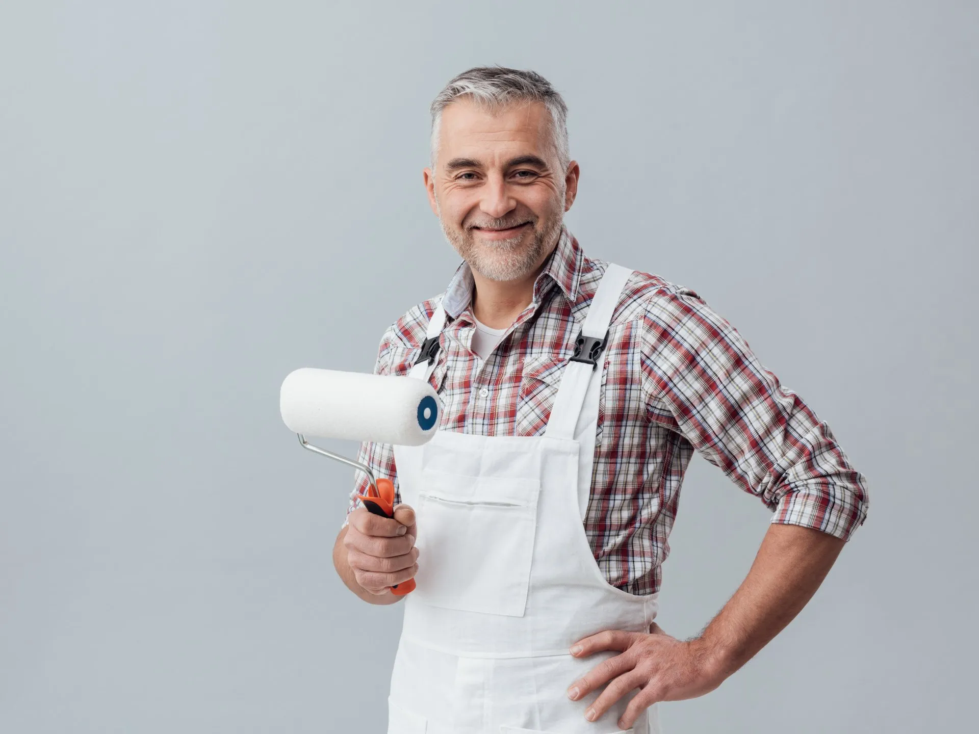 Smiling painter in white overalls holding a paint roller