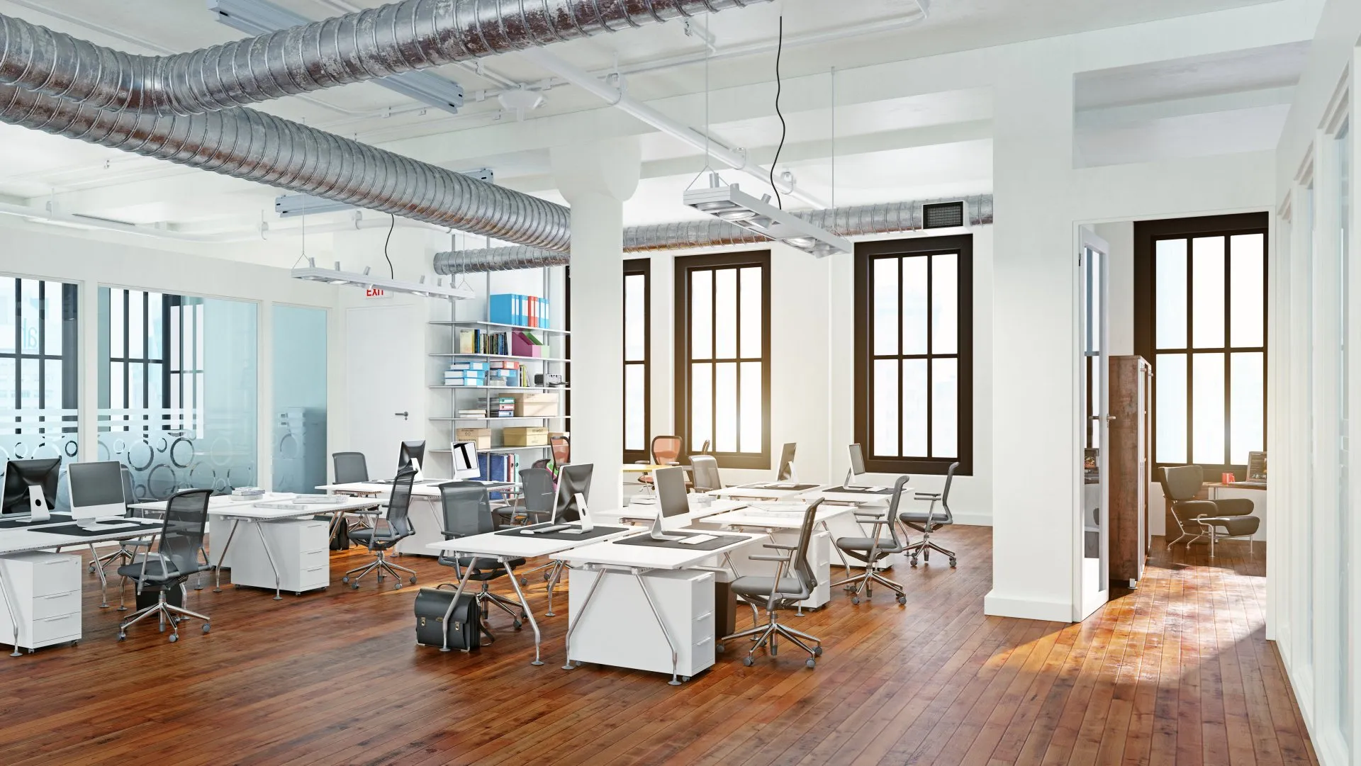 Bright open-plan office with white walls, exposed ductwork and wood floors