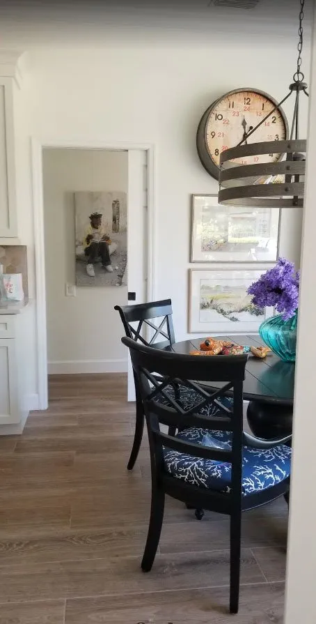 Breakfast nook with white walls, black dining chairs and a wall clock