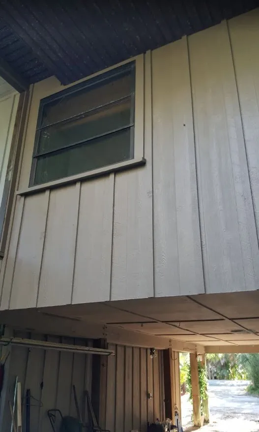 Light gray vertical board siding around a window on a raised home