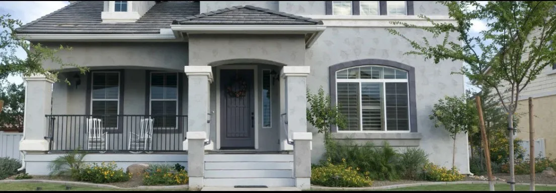 Gray two-story home with dark trim, arched window and covered front porch