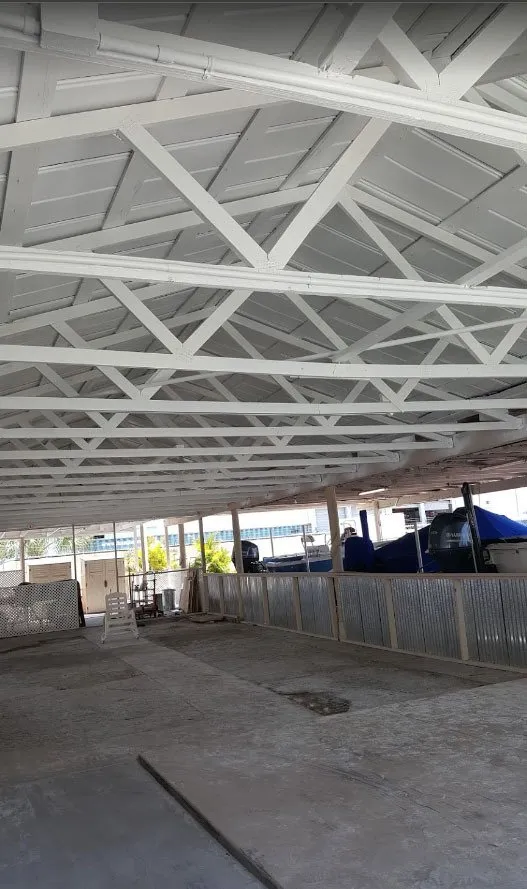 Large covered shed with white-painted roof trusses over a concrete floor
