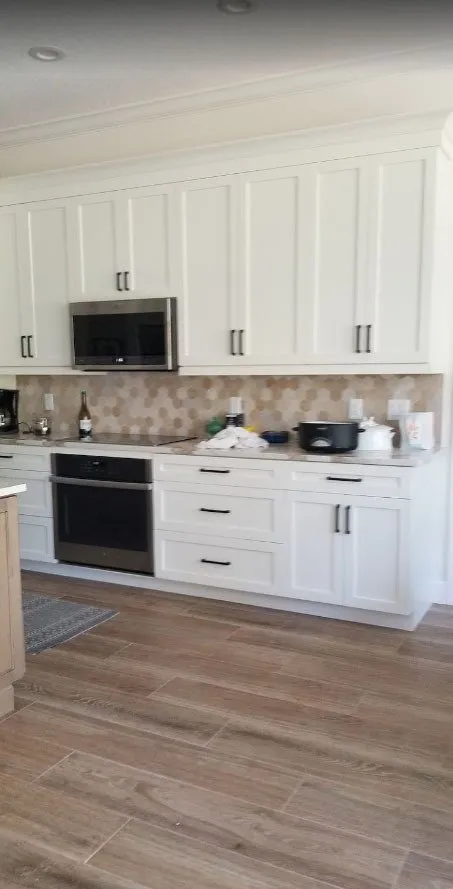 Kitchen with white shaker cabinets, hexagon tile backsplash and wood-look floors