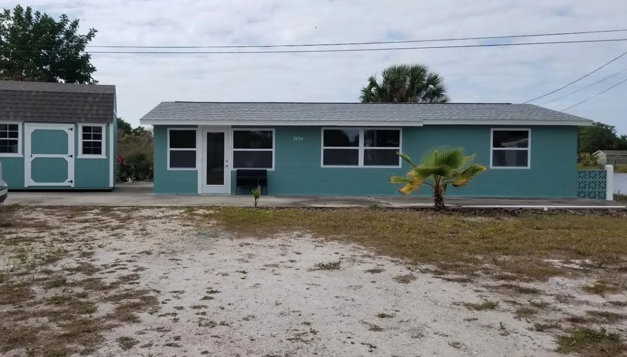 Teal single-story house with white trim and a matching teal shed