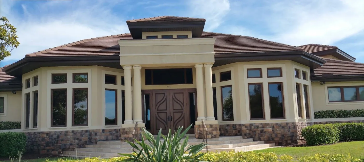 Cream stucco home with tile roof, columns and double wood front doors