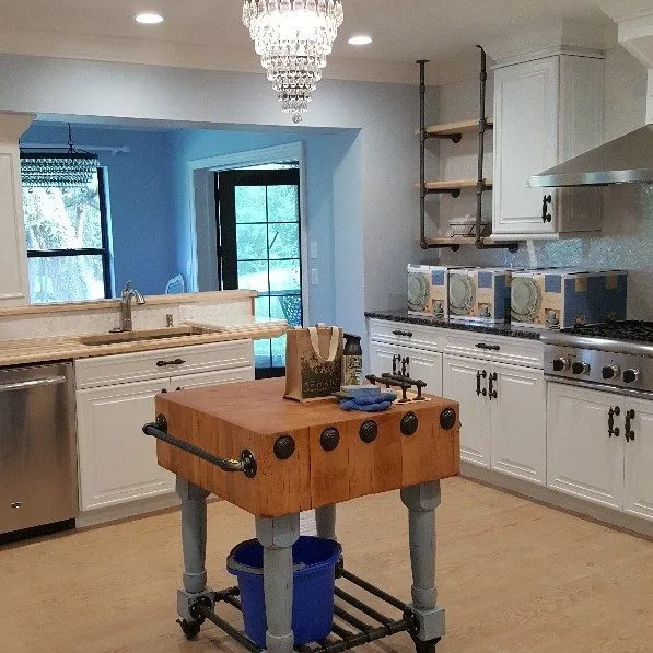 Renovated kitchen with white cabinets, blue walls and a butcher-block island