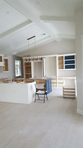 Kitchen under renovation with white vaulted plank ceiling and navy island