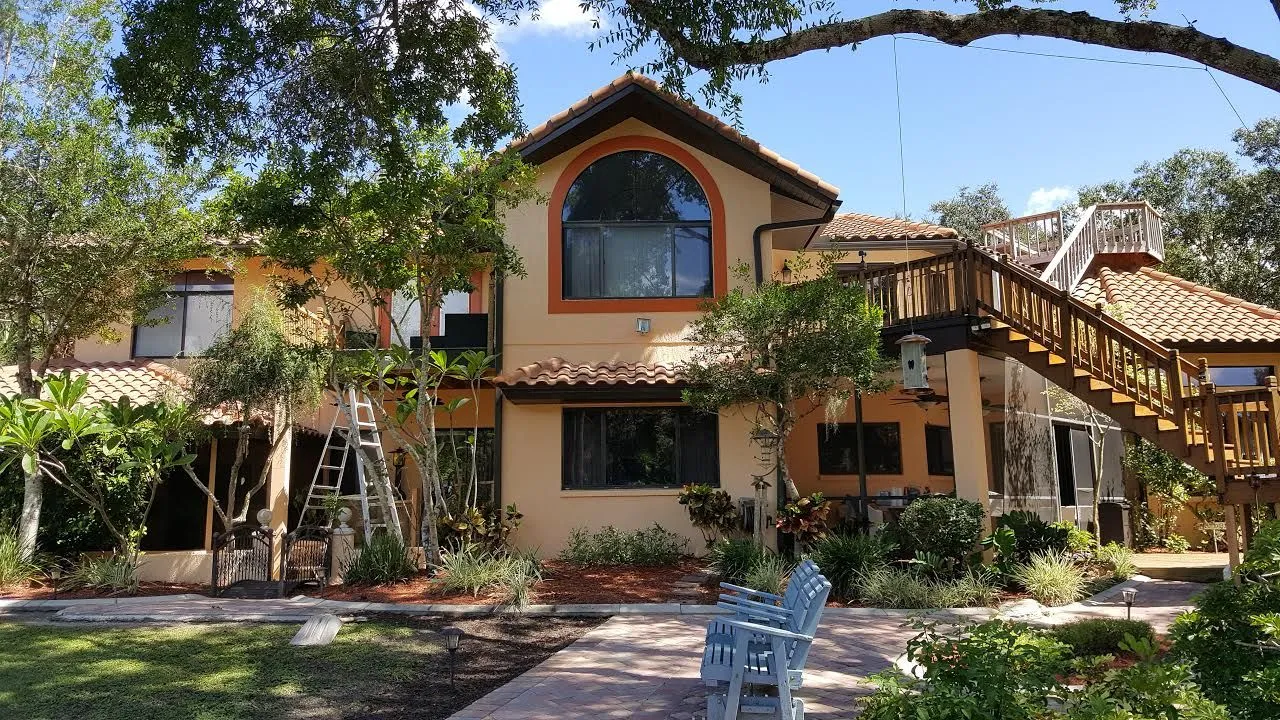 Two-story peach stucco home with orange trim and wooden exterior staircase